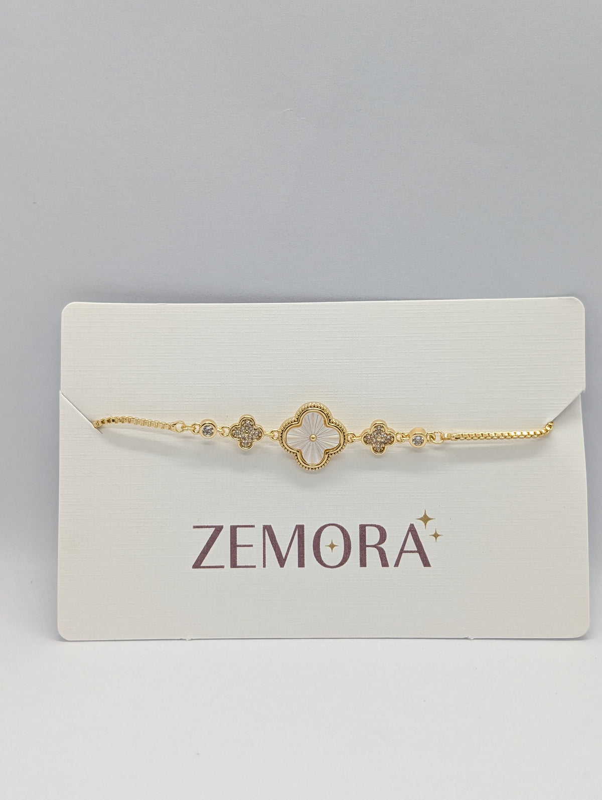 Yellow gold mother of pearl clover charm station bracelet on Zemora jewellery card
