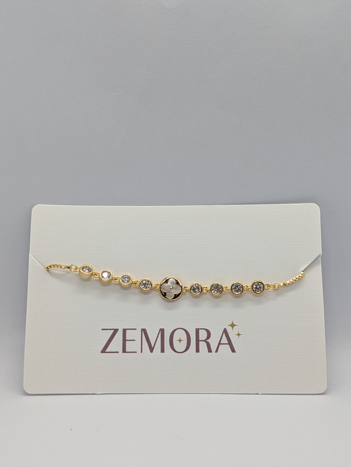 Rose gold CZ bezel clover bracelet with adjustable bolo slider flat lay product photography