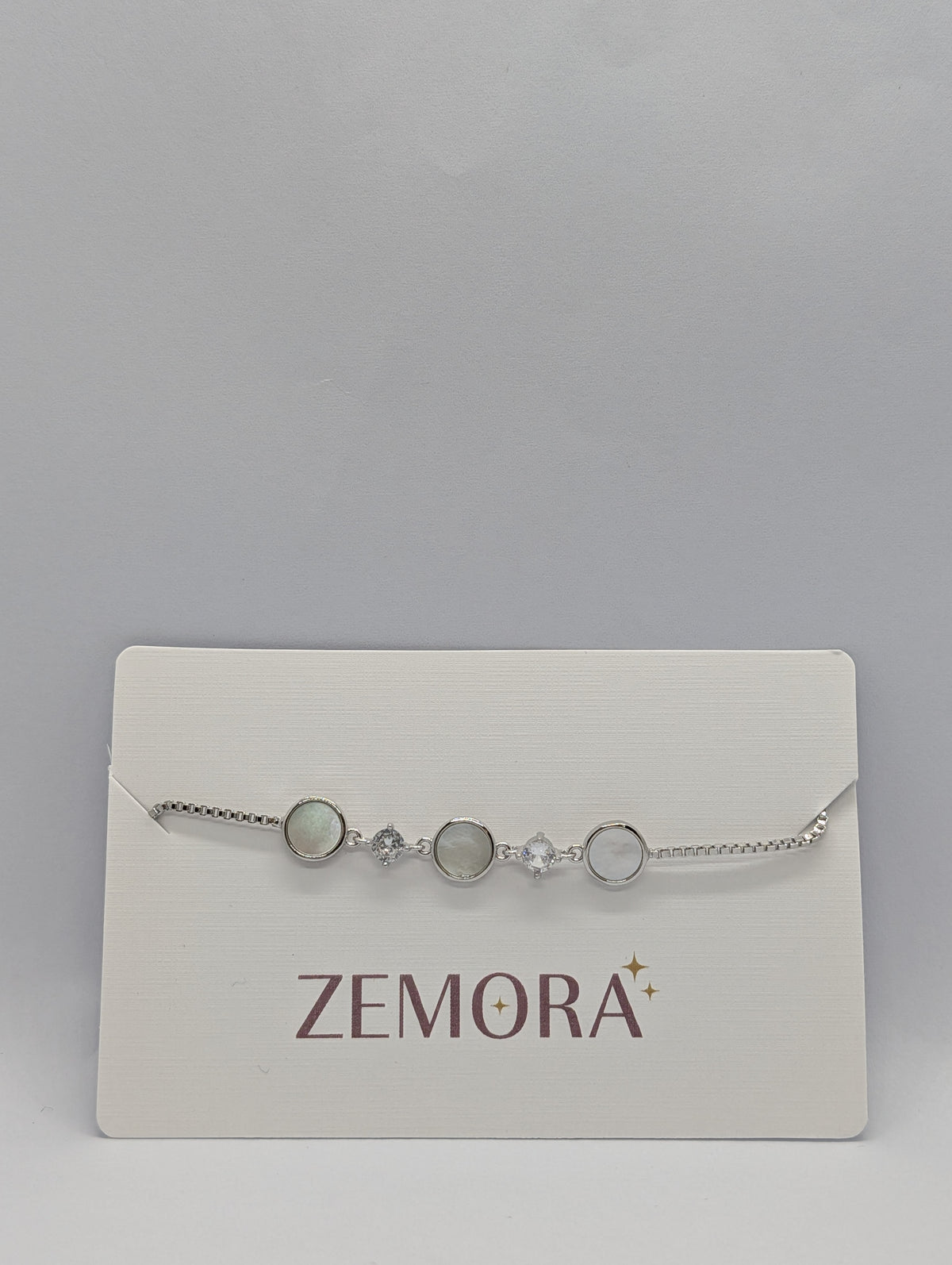 Silver luminous shell disc solitaire charm bracelet on Zemora jewellery card