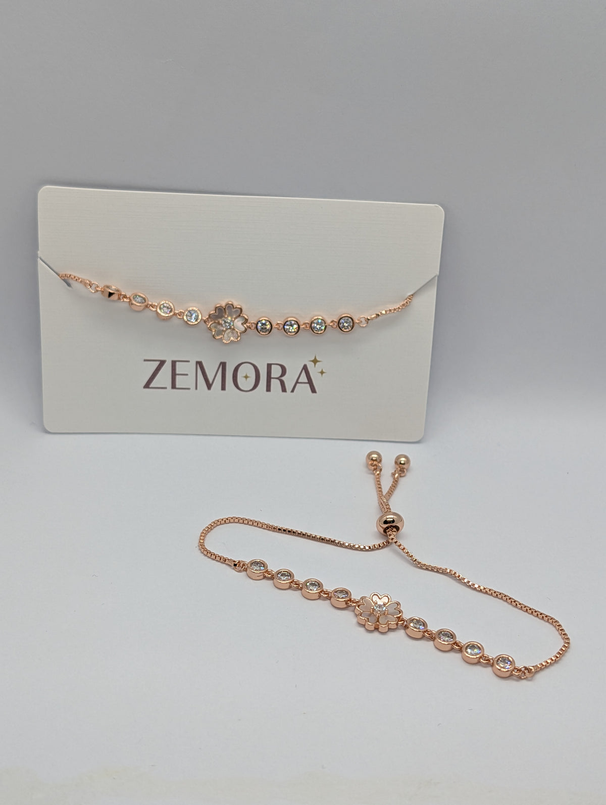 Yellow gold white enamel sakura flower bracelet close-up showing bezel solitaires and heart charm