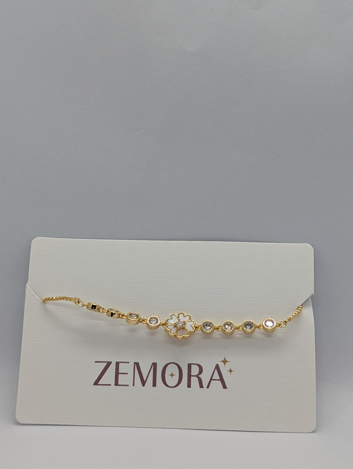 Rose gold white enamel sakura flower bracelet flat lay with adjustable bolo slider detail
