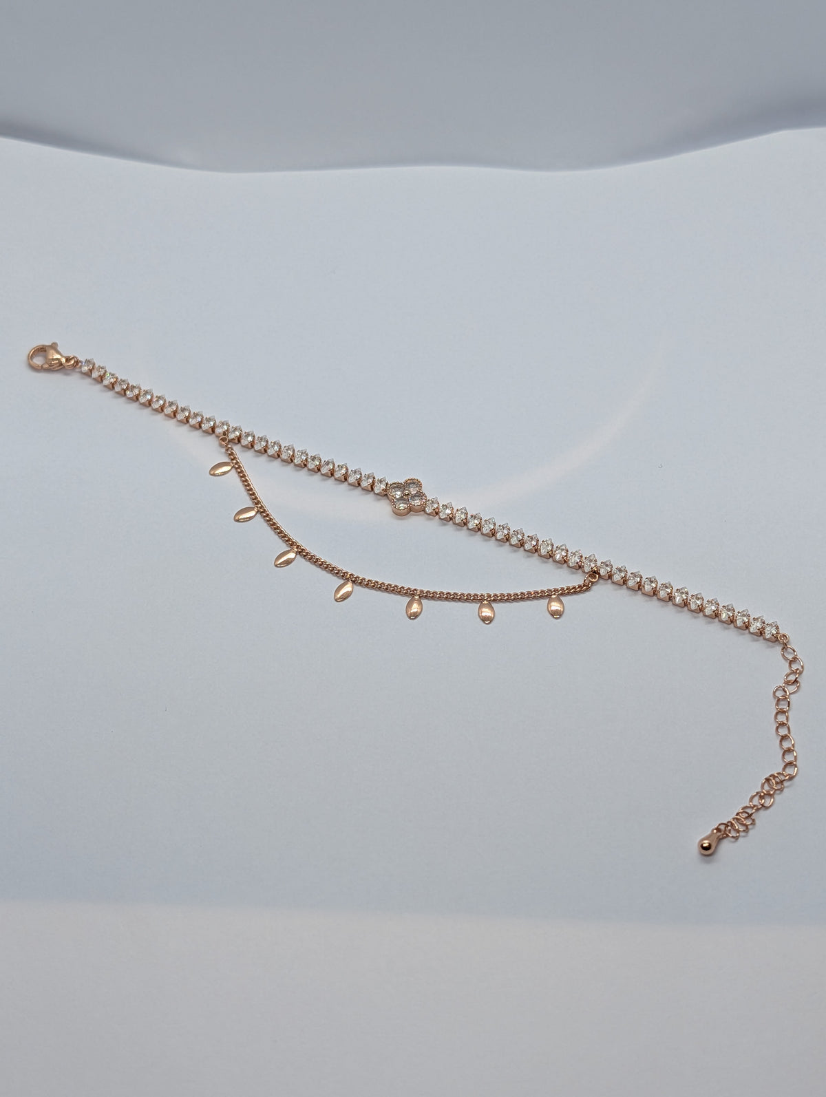 Rose gold double layer clover tennis and teardrop charm bracelet flat lay showing full length
