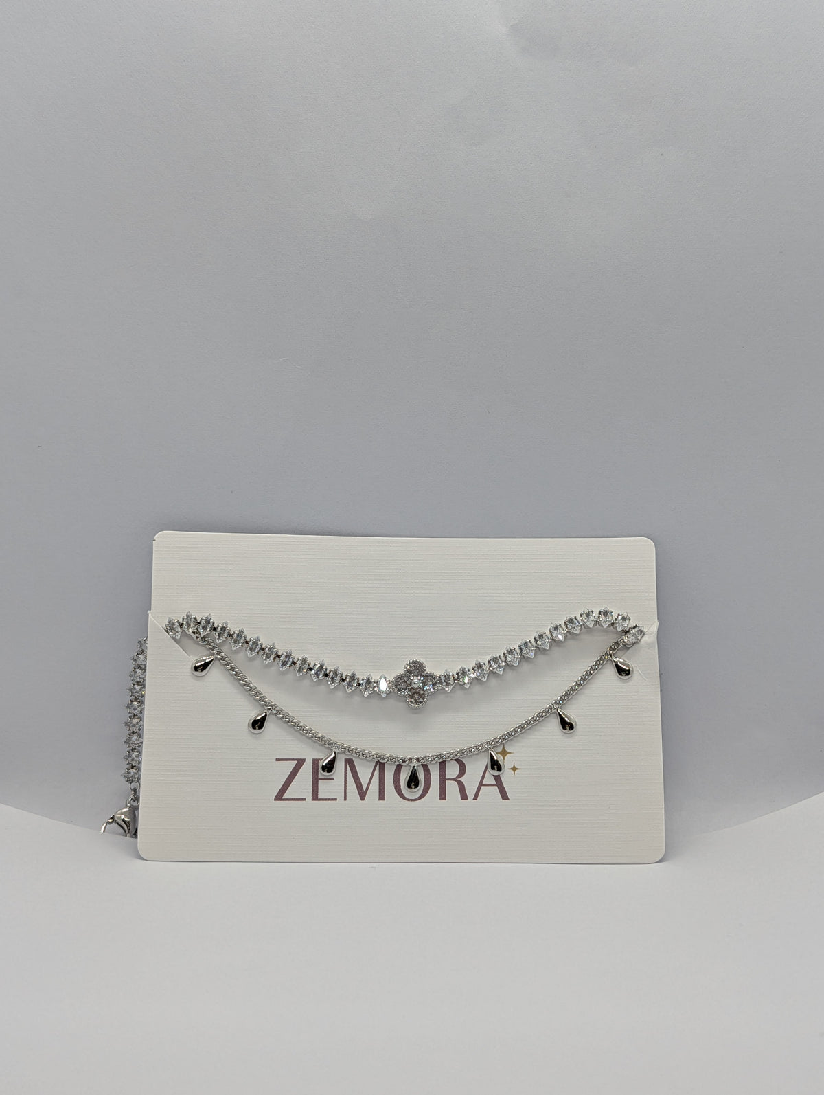Silver double layer clover tennis and teardrop charm bracelet flat lay showing full length