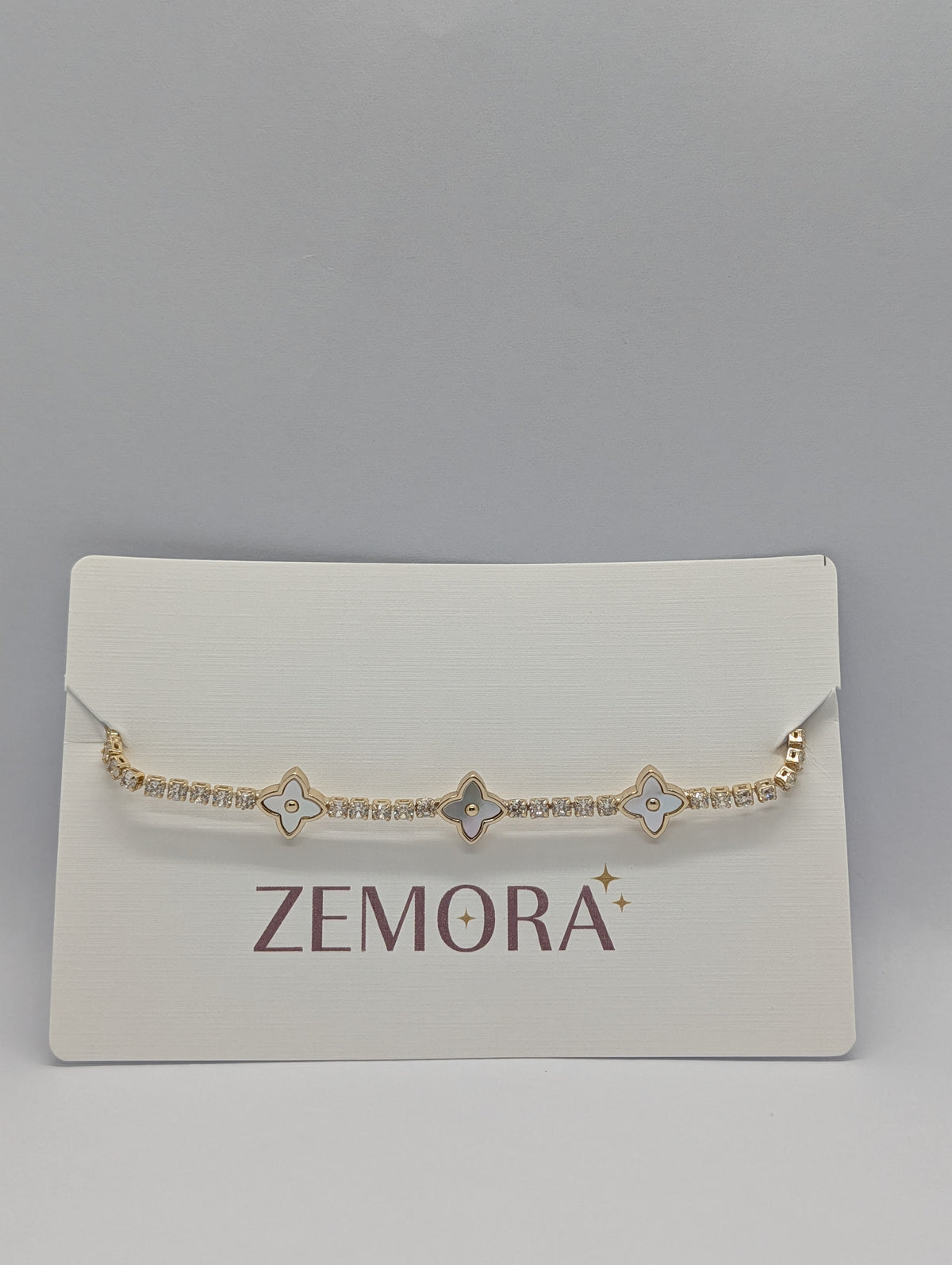 Yellow gold pearl quatrefoil station CZ tennis bracelet on Zemora jewellery card
