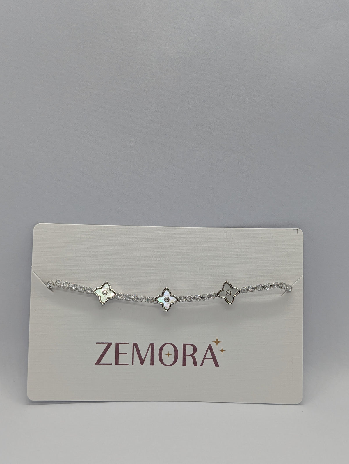 Rose gold pearl quatrefoil station CZ tennis bracelet flat lay showing full length and bolo slider