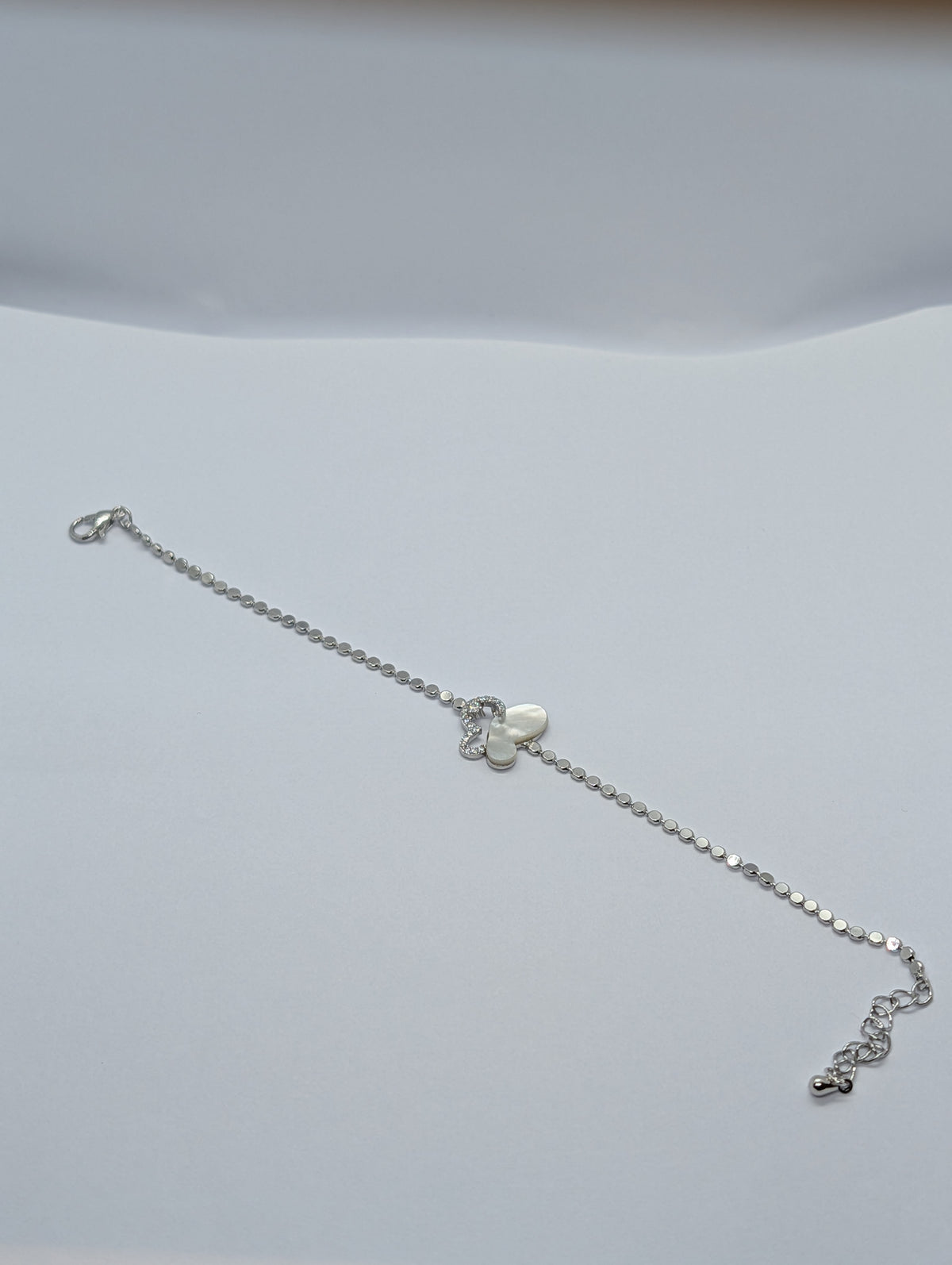 Rose gold pearl and pavé half butterfly sequin chain bracelet flat lay showing full length and extender chain