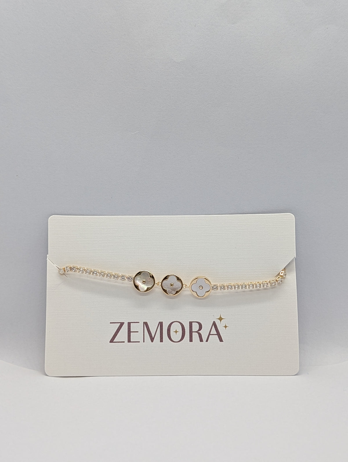Yellow gold dual-tone pearl clover trio CZ tennis bracelet flat lay full length with box clasp