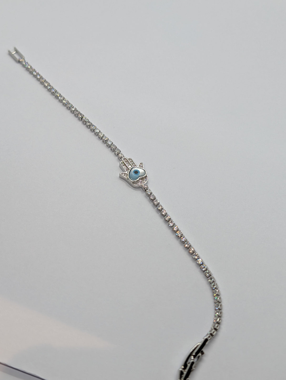 Silver evil eye Hamsa hand station CZ tennis bracelet flat lay showing full length and box clasp