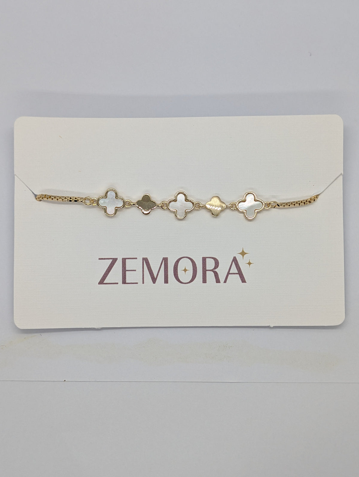 Mother of Pearl Onyx Clover Station Bracelet - Rose Gold tone driftwood lifestyle flat lay with palm shadow