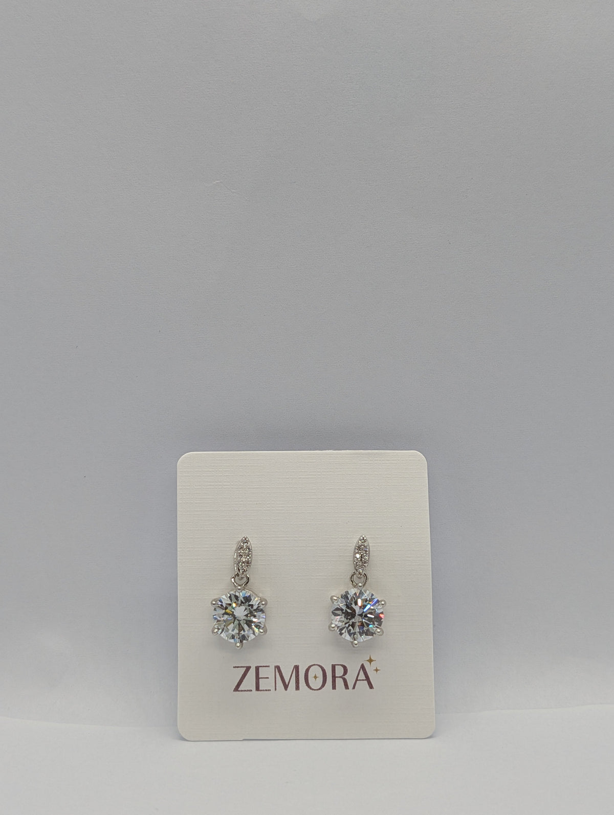 CZ Solitaire Drop Huggie Earrings - Silver tone pair on Zemora card display