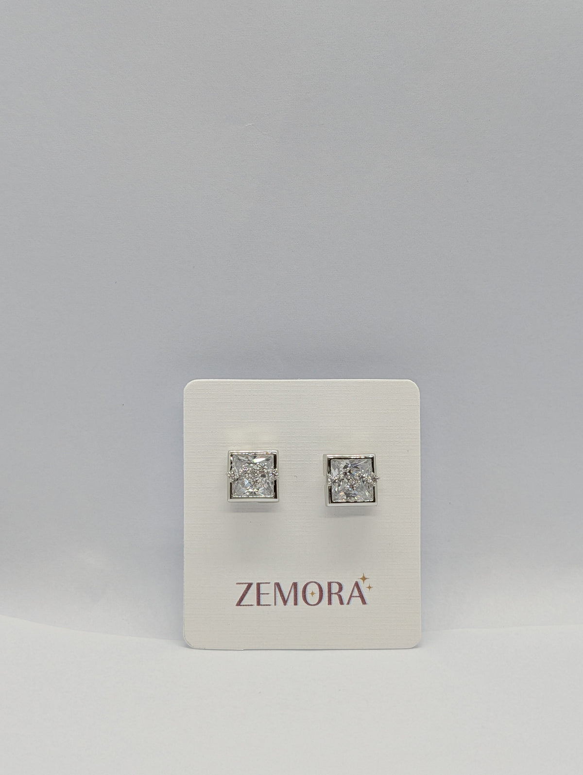 Princess Cut CZ Square Bezel Stud Earrings - Silver tone pair on Zemora card display
