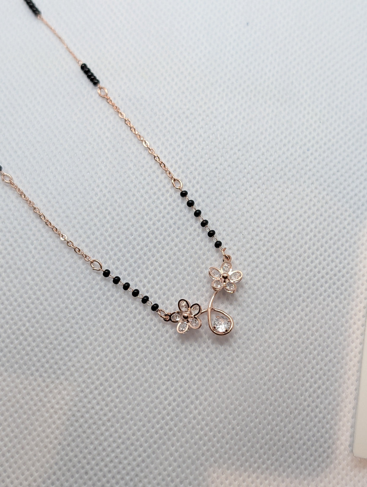 CZ Twin Flower Teardrop Mangalsutra - Rose Gold tone full view on white fabric display stand