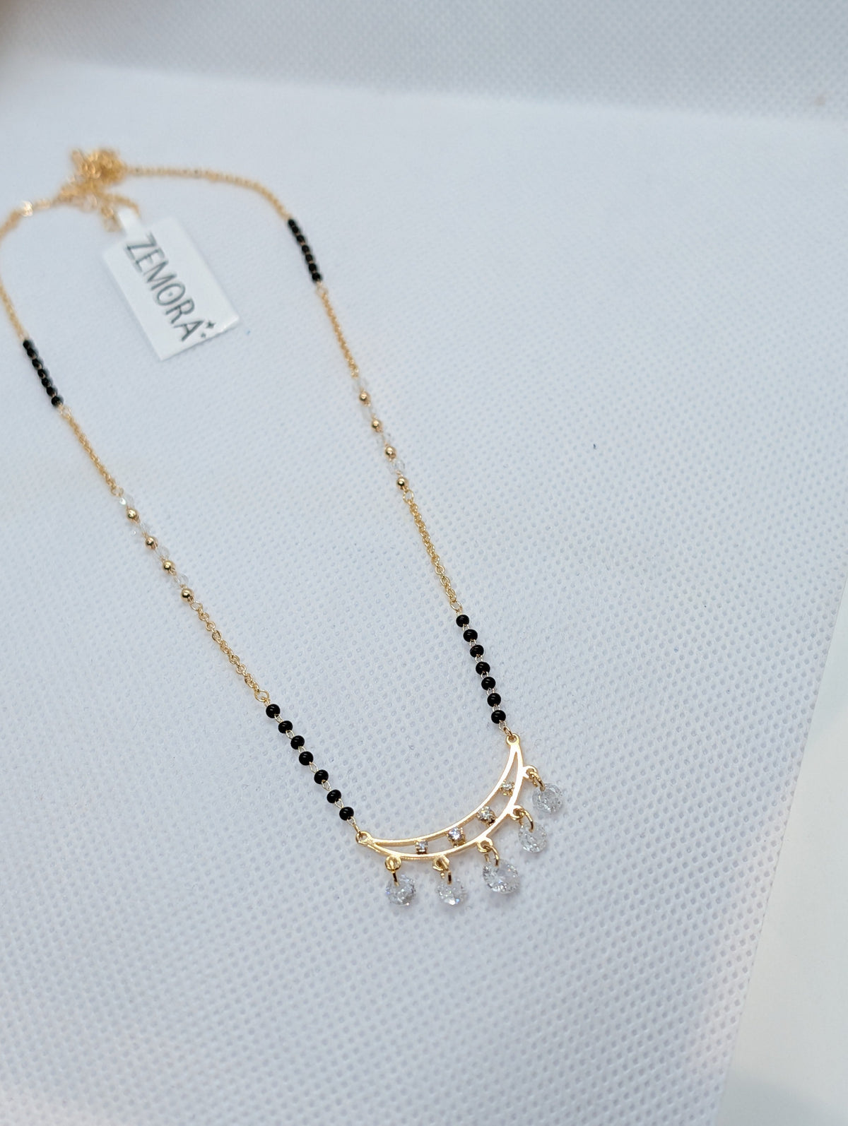CZ Crescent Arc Multi-Drop Mangalsutra - Gold tone full view with Zemora tag on white fabric display