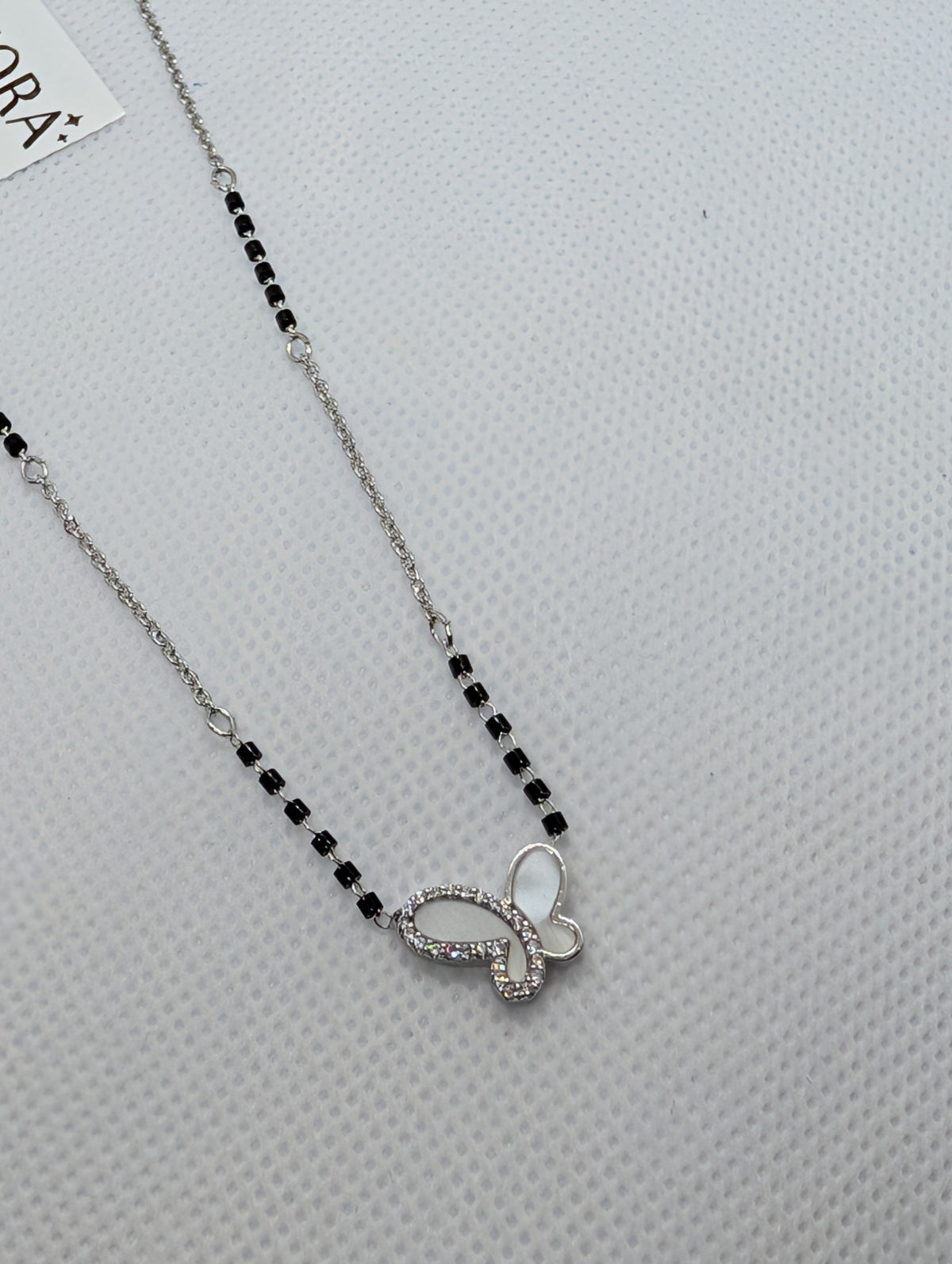 CZ Mother of Pearl Butterfly Mangalsutra - Gold tone full length flat lay with Zemora tag on white fabric