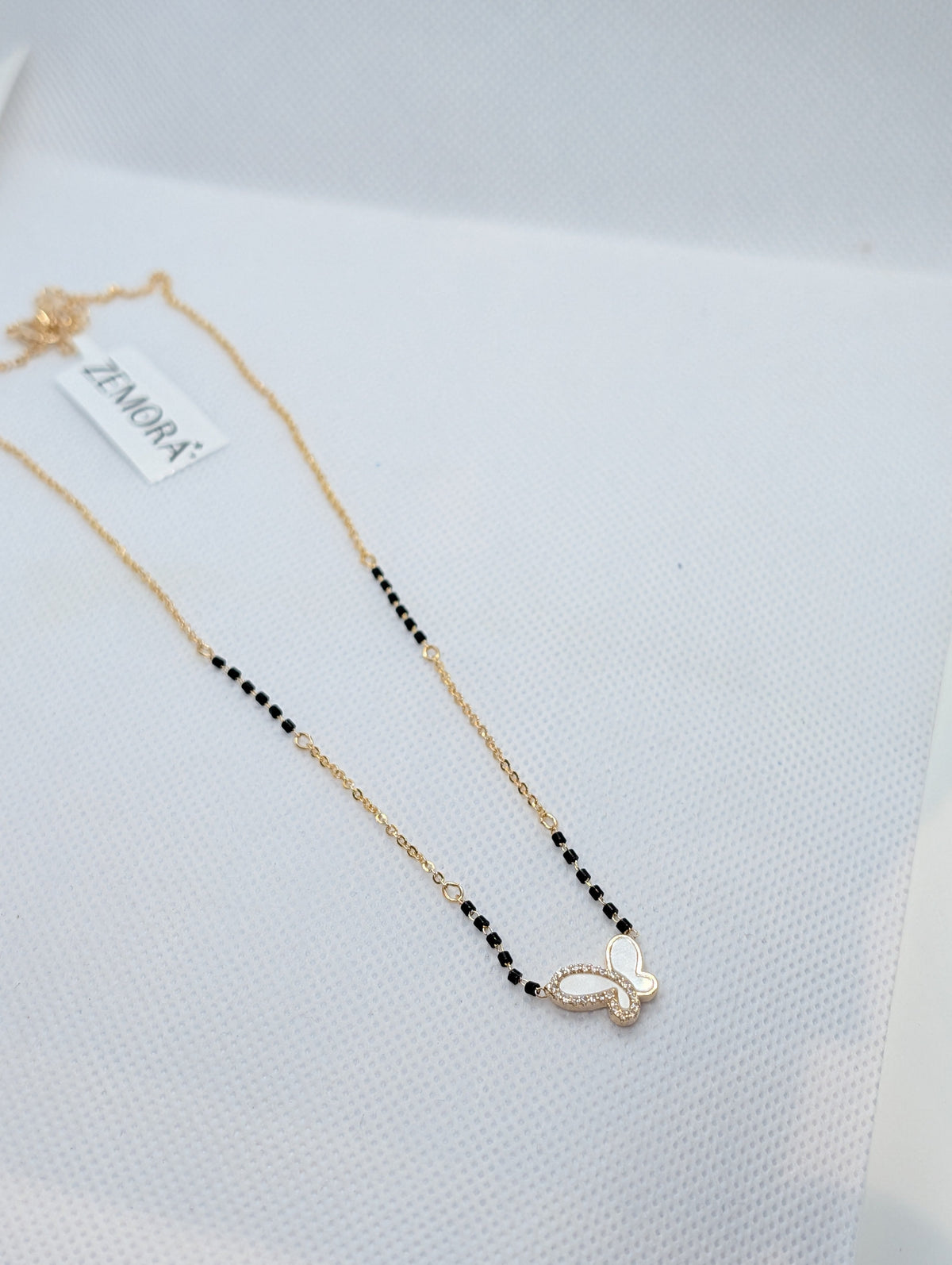 CZ Mother of Pearl Butterfly Mangalsutra - Gold tone top view flat lay on white fabric
