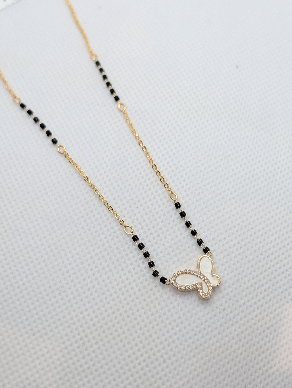 CZ Mother of Pearl Butterfly Mangalsutra - Gold tone full length flat lay on white background