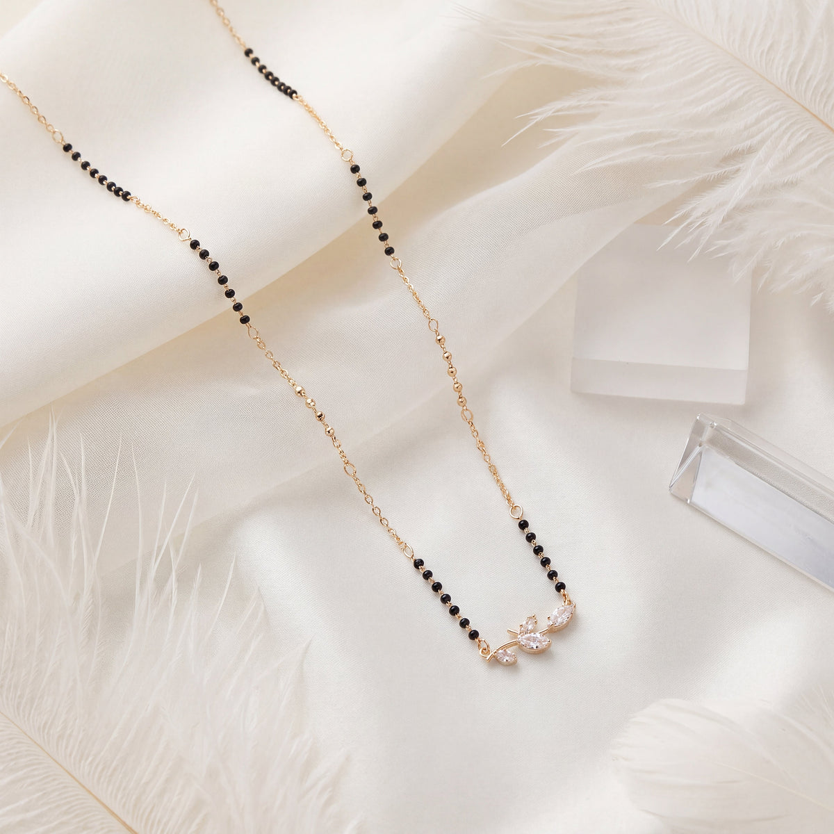 CZ Marquise Leaf Branch Mangalsutra - Gold tone lifestyle flat lay on white fur with crystal accent