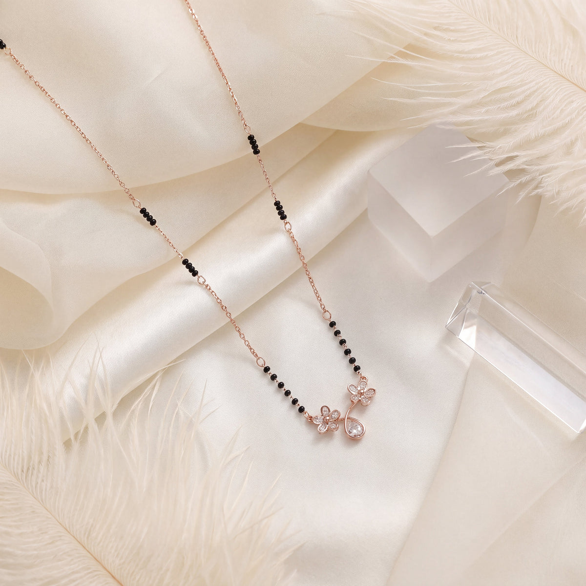 CZ Twin Flower Teardrop Mangalsutra - Rose Gold tone lifestyle flat lay on white fur and silk with crystal accent