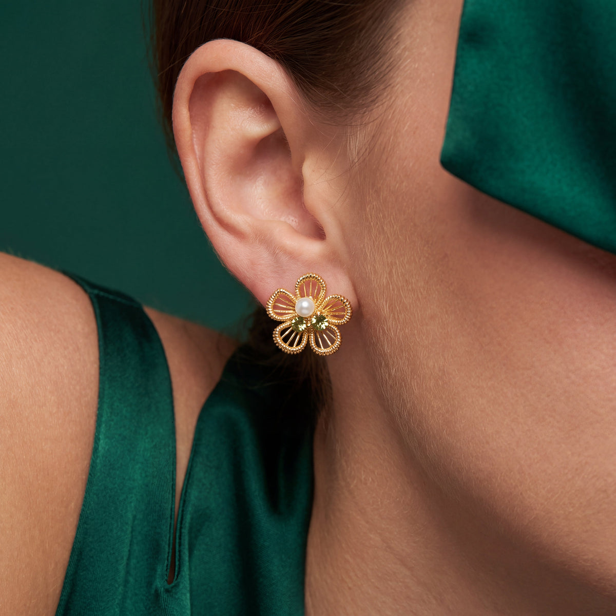 Filigree Flower Pearl Peridot CZ Stud Earrings - Gold tone worn on model's ear with green background