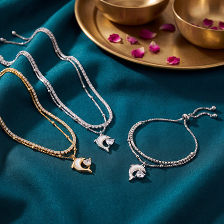 CZ Dolphin Charm Double Layer Bracelet - Silver and Gold tone lifestyle flat lay on teal velvet with rose petals and brass bowls