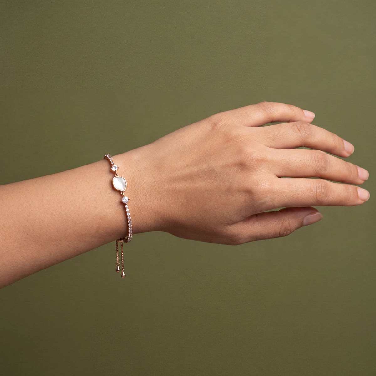 Mother of Pearl Hexagon CZ Tennis Bracelet - Rose Gold tone worn on wrist against olive green background
