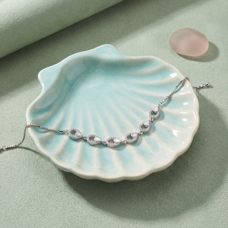 CZ Mother of Pearl Teardrop Link Bracelet - Silver tone lifestyle flat lay on seafoam ceramic shell dish with rose quartz